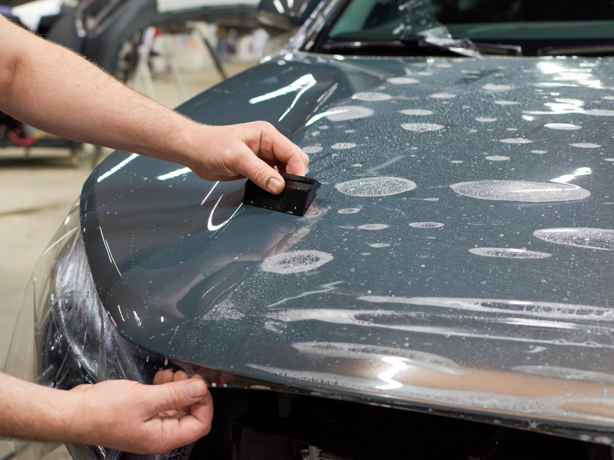 Applying a protective film coat to a car, showcasing a method for safeguarding the vehicle's paint from scratches, chips, and environmental damage.