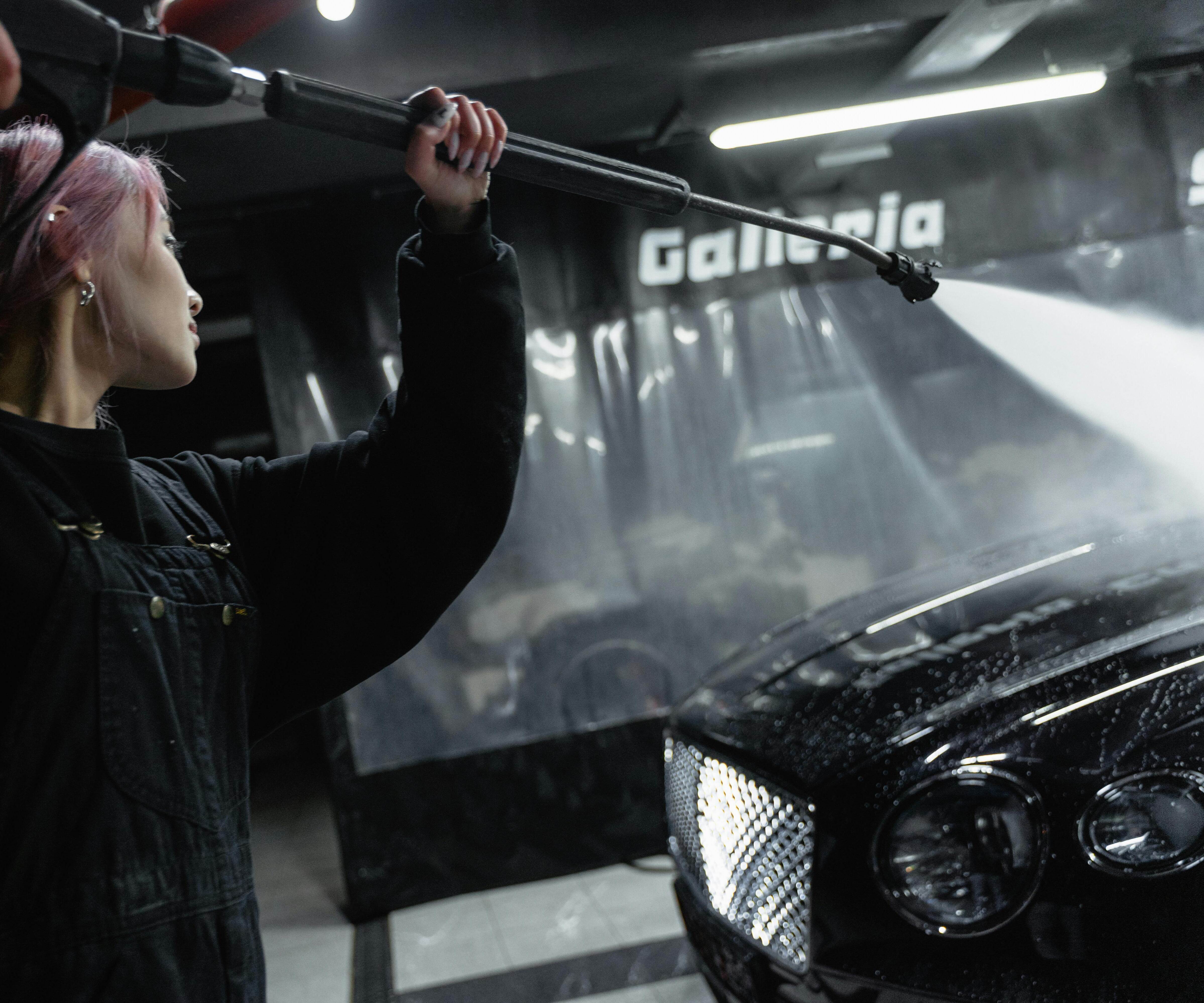 A woman power washing a car