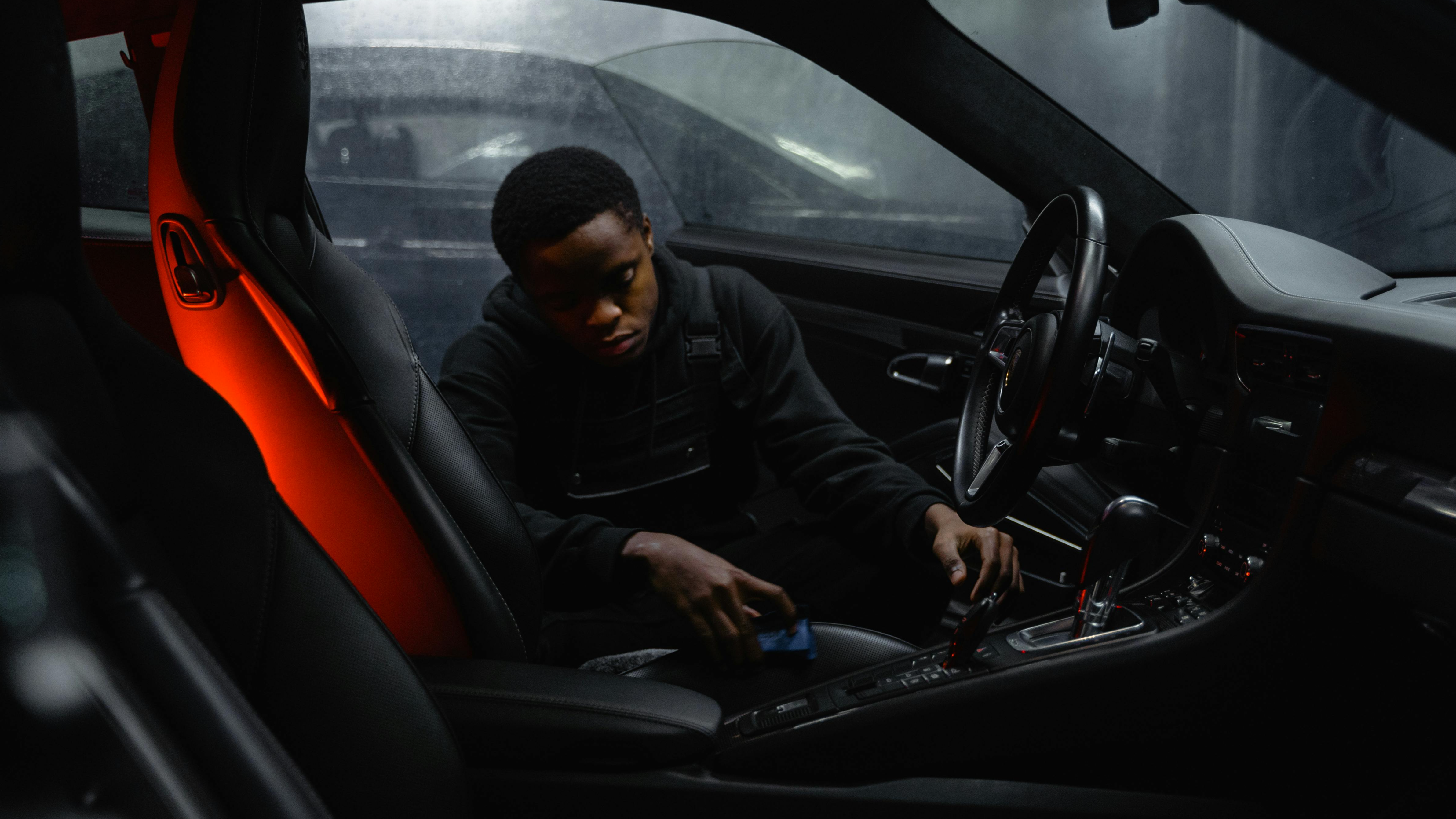 Person cleaning a car's surface with a microfiber cloth during a detailing session